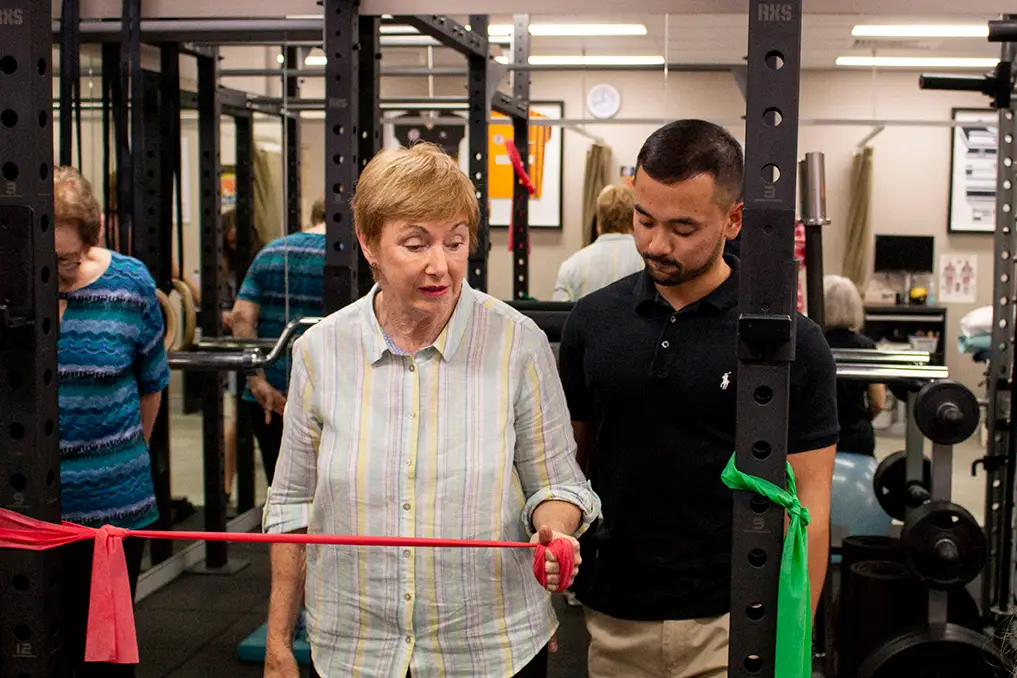 Woman and trainer practicing shoulder warm up exercises | Featured image for Shoulder Warm Up Exercises blog for Pivotal Motion Physiotherapy.