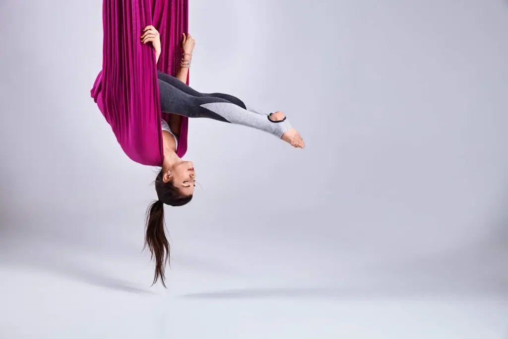 Acrobat hanging upside down in cloth.