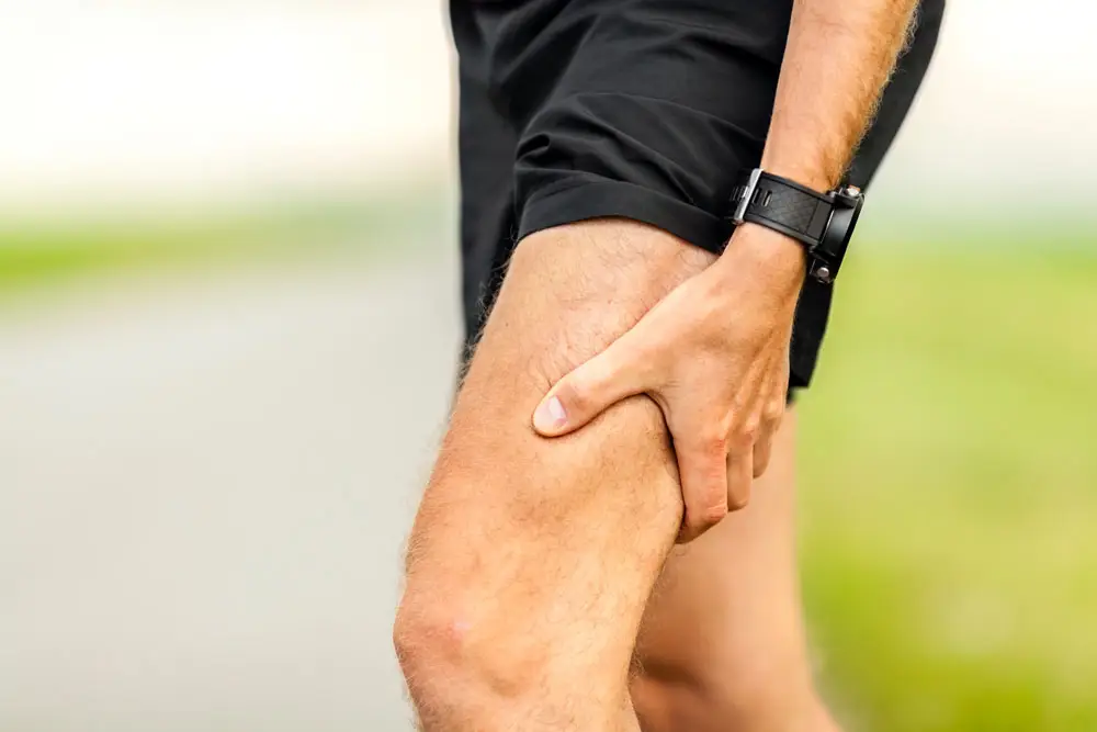 A close up of a man holding the back of his thigh | Featured image on Hamstring Injury.