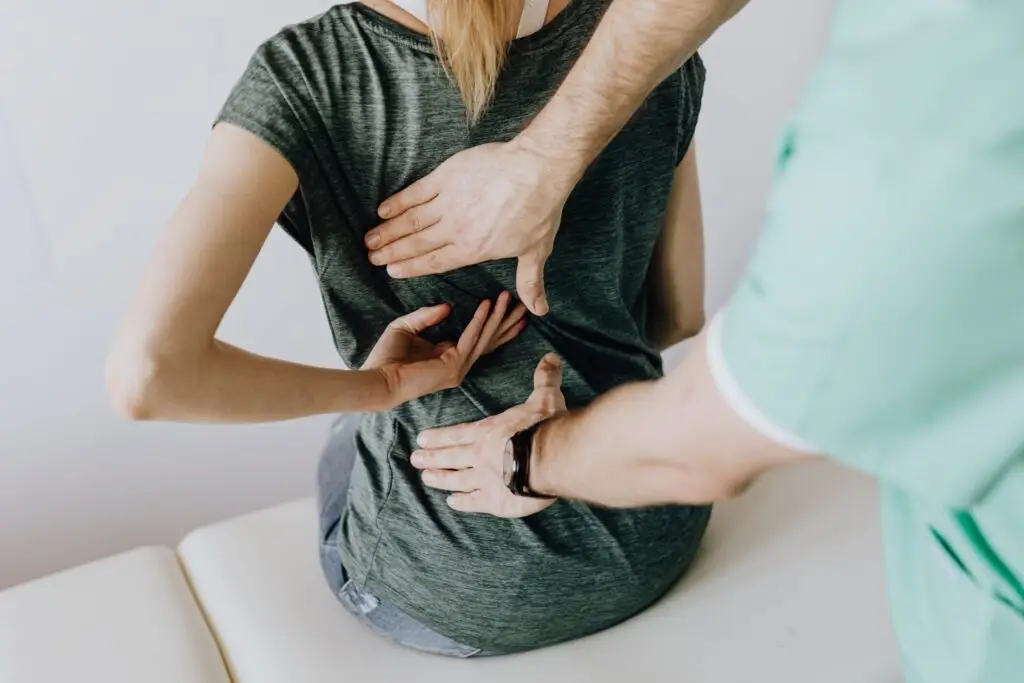 A woman with back pain sitting down while her back is being readjusted | Featured image on Why Doesn't to my Type of Pain.