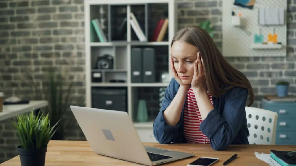 a sad woman looking at her laptop